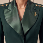 GLORY upper-front detail showing broad green silk lapels, gold stars and the Saudi emblem.
