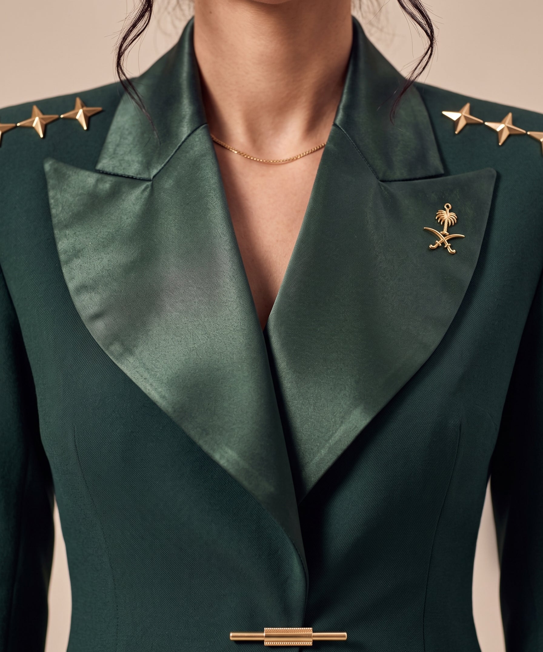GLORY upper-front detail showing broad green silk lapels, gold stars and the Saudi emblem.