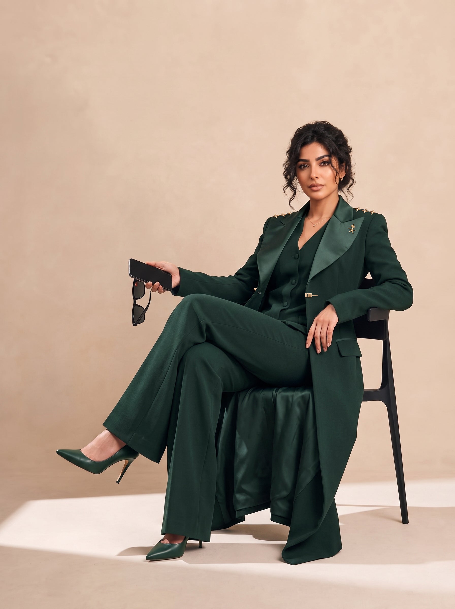 GLORY long blazer styled with a coordinating vest and trousers in a seated editorial pose.