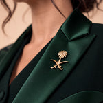 NAKHLAH green silk lapel close-up with the gold Saudi palm-and-crossed-swords emblem.