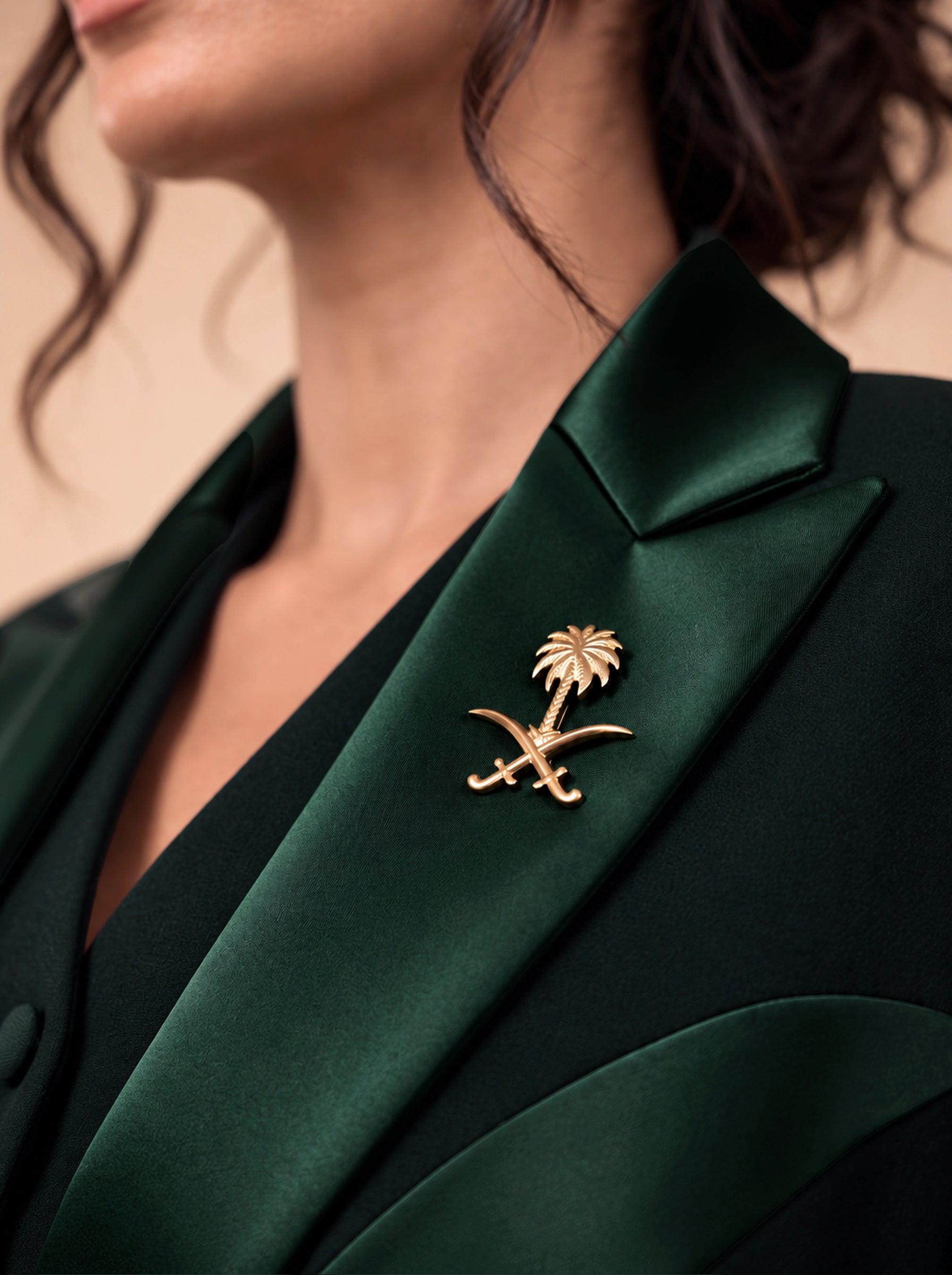 NAKHLAH green silk lapel close-up with the gold Saudi palm-and-crossed-swords emblem.