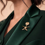 NAKHLAH lapel close-up with the gold Saudi palm-and-crossed-swords emblem.