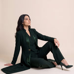 TERRA long blazer styled open with a coordinating vest and trousers in a seated editorial pose.