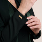 TERRA sleeve cuff close-up with the gold-tone VEORA nameplate and crepe fabric texture.