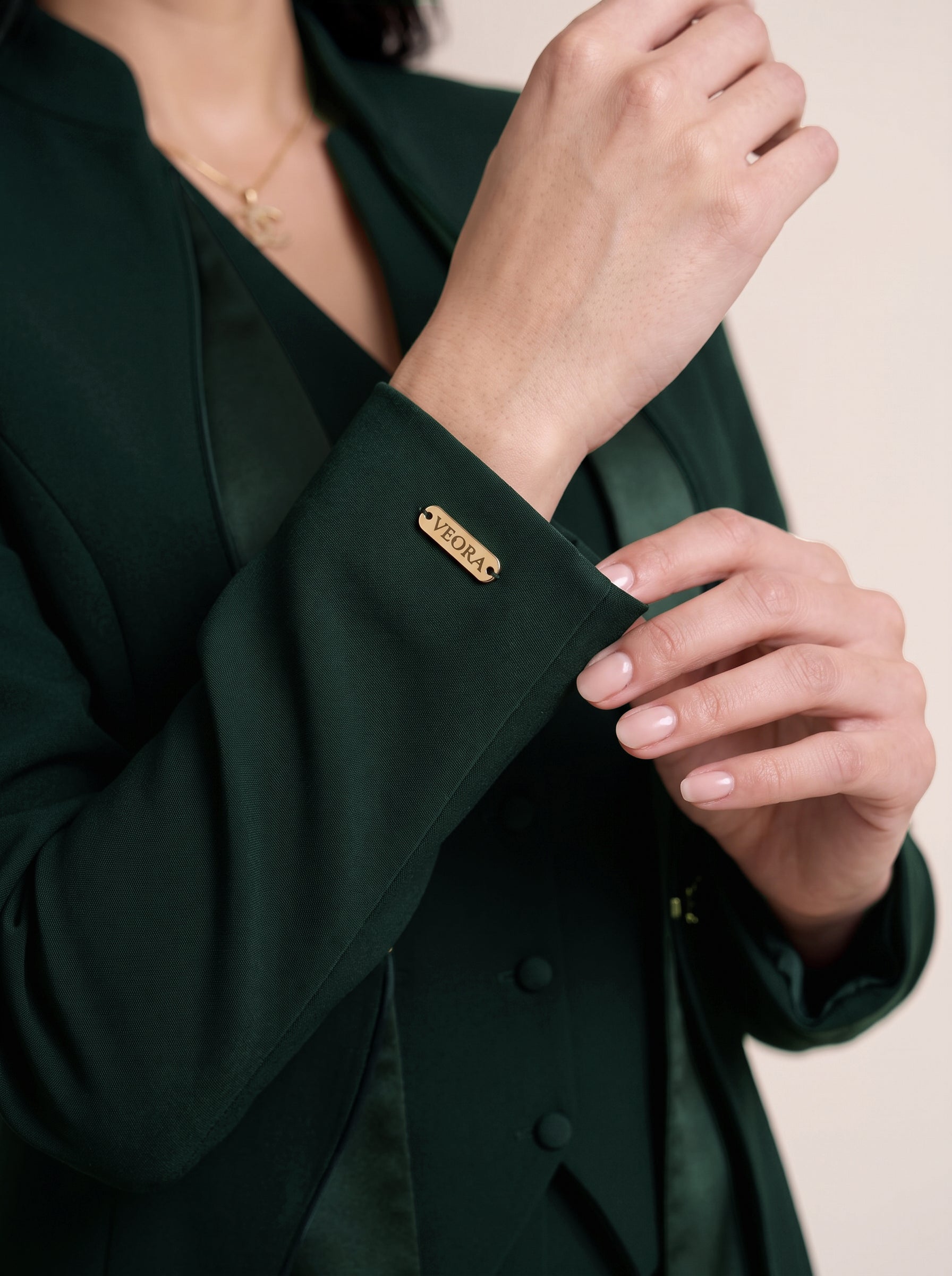 TERRA sleeve cuff detail with gold-tone VEORA nameplate.